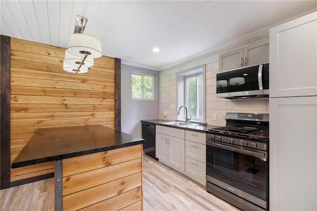 kitchen featuring stainless steel appliances, sink, white cabinets, light hardwood / wood-style floors, and hanging light fixtures