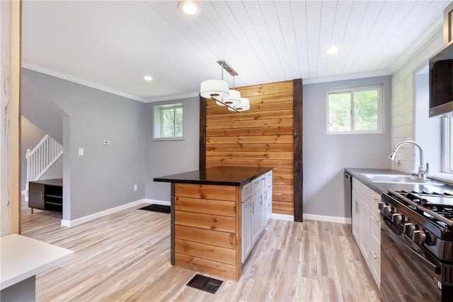 kitchen with pendant lighting, sink, light wood-type flooring, gas stove, and white cabinetry