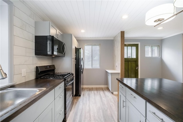 kitchen featuring butcher block counters, sink, light hardwood / wood-style flooring, black appliances, and ornamental molding