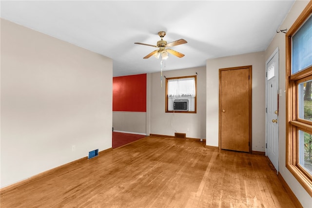 empty room featuring wood-type flooring, ceiling fan, and a healthy amount of sunlight