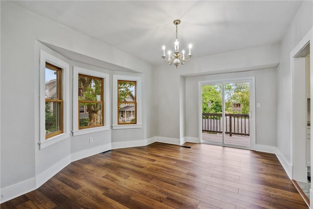 unfurnished dining area with dark hardwood / wood-style flooring, a healthy amount of sunlight, and a notable chandelier