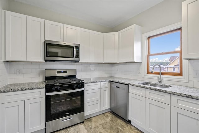 kitchen featuring light stone countertops, white cabinetry, sink, and appliances with stainless steel finishes