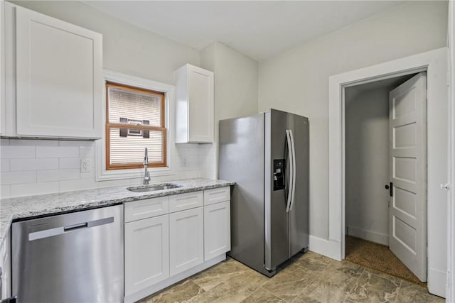 kitchen featuring backsplash, white cabinets, sink, appliances with stainless steel finishes, and light stone counters