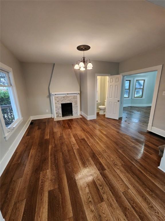 unfurnished living room featuring a chandelier, dark hardwood / wood-style floors, and a fireplace