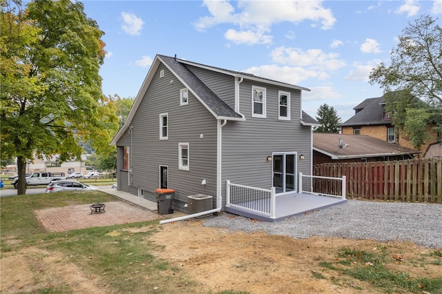 back of property with cooling unit, a fire pit, a lawn, and a patio