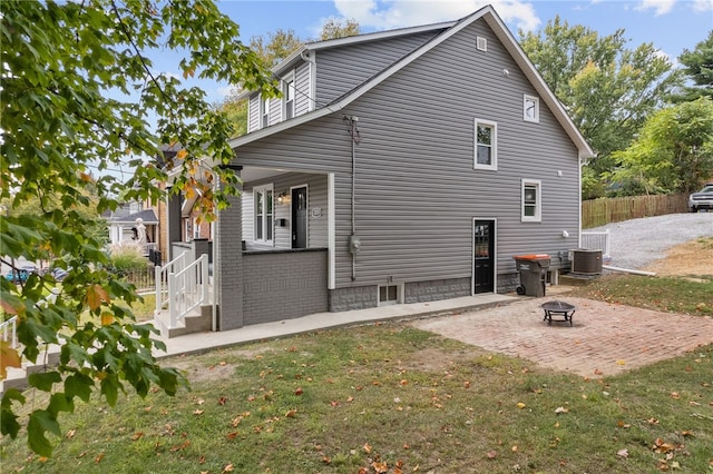 rear view of property with a fire pit, a yard, a patio area, and central air condition unit