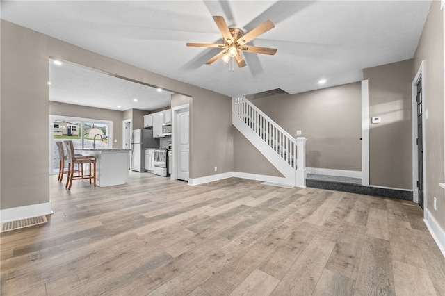 unfurnished living room with ceiling fan and light wood-type flooring