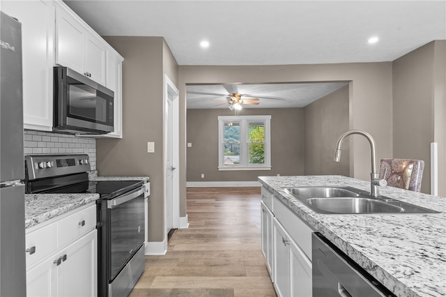 kitchen with white cabinets, light hardwood / wood-style floors, appliances with stainless steel finishes, and ceiling fan