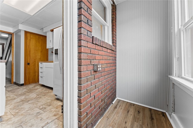 laundry room with brick wall and light hardwood / wood-style floors