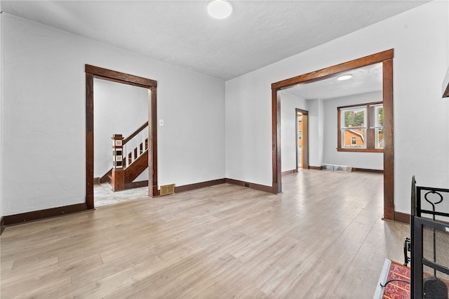 empty room with a textured ceiling and light hardwood / wood-style flooring