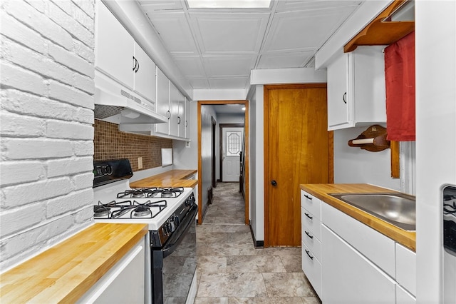 kitchen with sink, white cabinets, gas range oven, and decorative backsplash