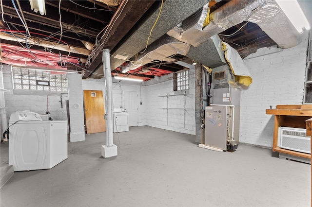 basement with washing machine and clothes dryer, heating unit, and an AC wall unit