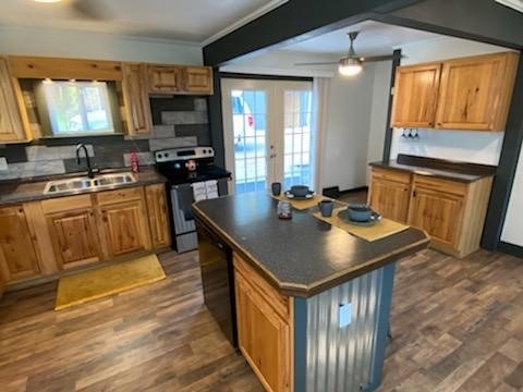 kitchen featuring tasteful backsplash, sink, stainless steel range with electric stovetop, a center island, and dark hardwood / wood-style flooring