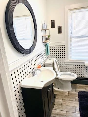 bathroom with vanity, toilet, hardwood / wood-style flooring, and baseboard heating