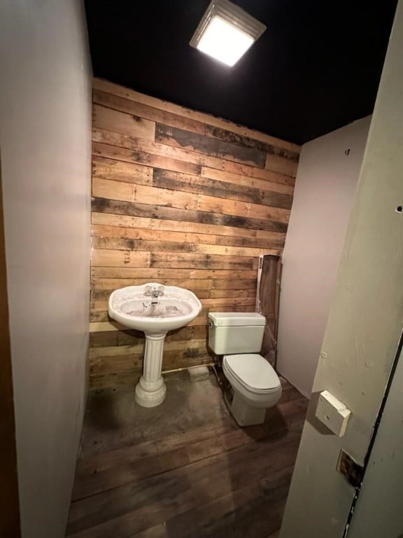 bathroom featuring toilet, hardwood / wood-style flooring, and wooden walls