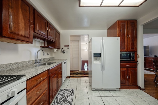 kitchen featuring light stone counters, appliances with stainless steel finishes, light tile patterned floors, and sink