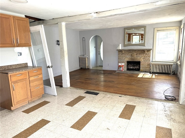 interior space featuring radiator, a textured ceiling, light hardwood / wood-style flooring, and a fireplace