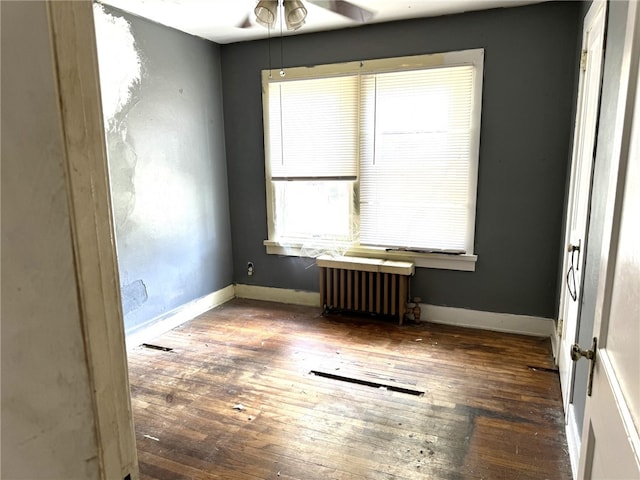 unfurnished room with dark hardwood / wood-style floors, radiator heating unit, and ceiling fan