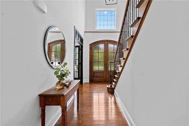 foyer featuring a healthy amount of sunlight, a towering ceiling, and hardwood / wood-style floors