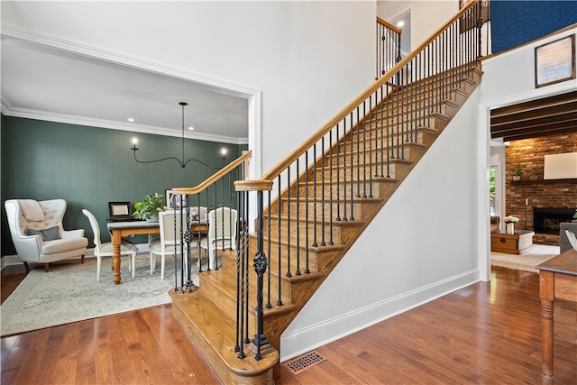 stairs with ornamental molding, wood-type flooring, and a fireplace