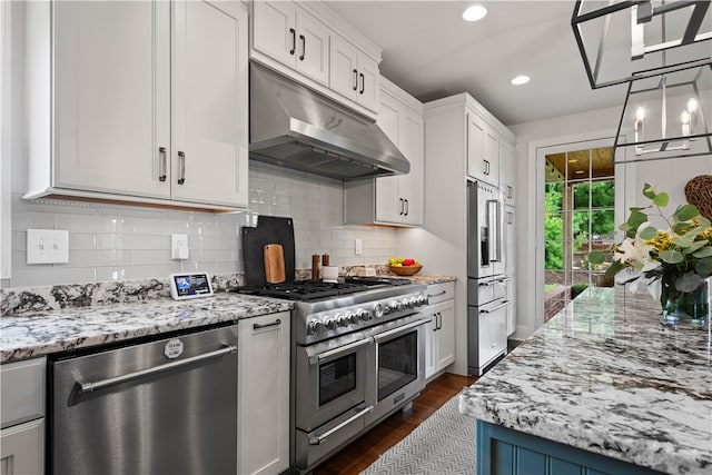 kitchen featuring light stone counters, dark wood-type flooring, white cabinets, premium appliances, and backsplash