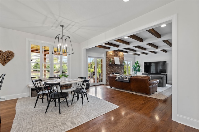 dining room with an inviting chandelier, a brick fireplace, beamed ceiling, and hardwood / wood-style floors