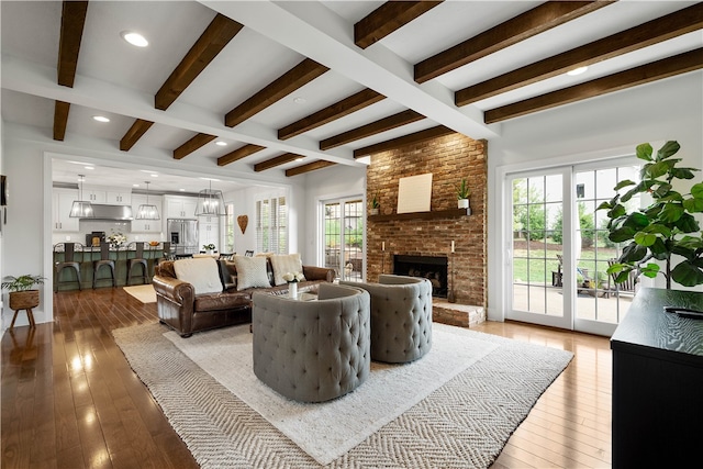 living room featuring a fireplace, beam ceiling, hardwood / wood-style floors, and a wealth of natural light