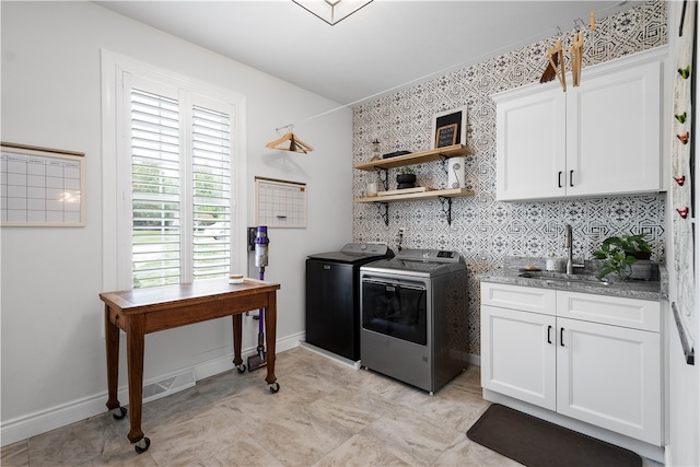 kitchen featuring decorative backsplash, white cabinetry, light stone countertops, sink, and washer and dryer