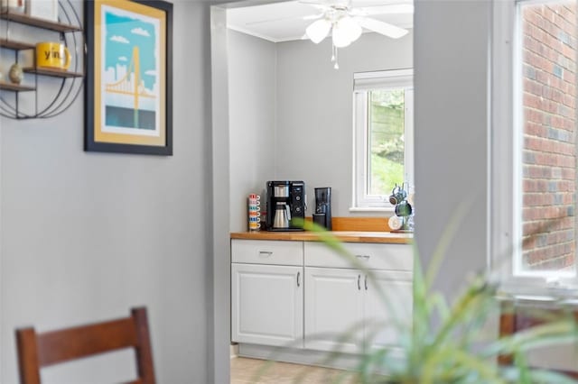 interior space featuring ceiling fan, white cabinets, and wood counters