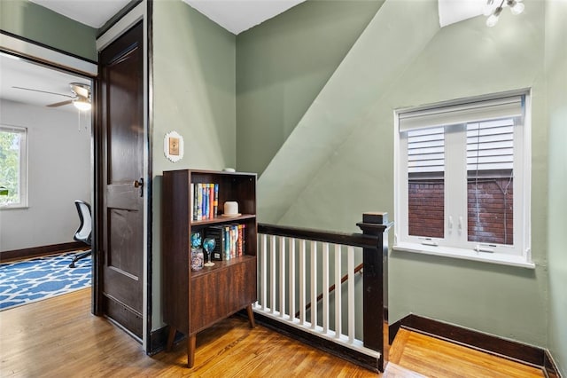 stairway with ceiling fan, hardwood / wood-style flooring, and lofted ceiling