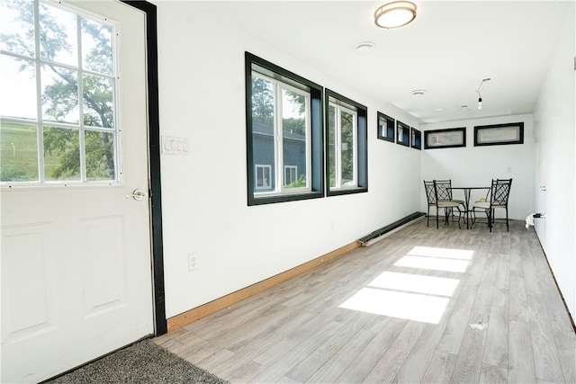 interior space with a baseboard heating unit, plenty of natural light, and hardwood / wood-style floors