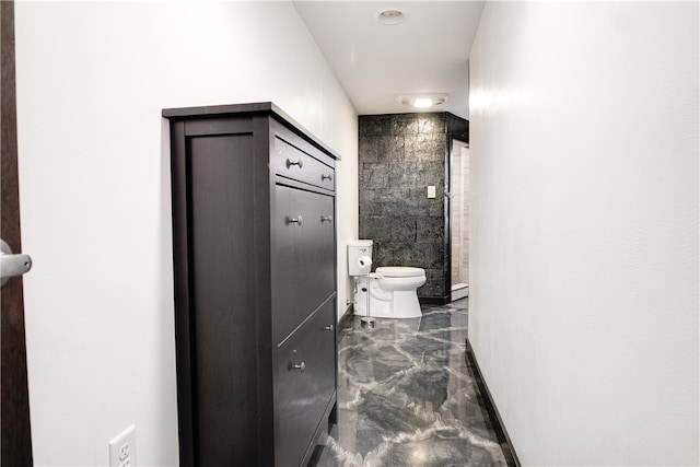 bathroom featuring a tile shower and toilet