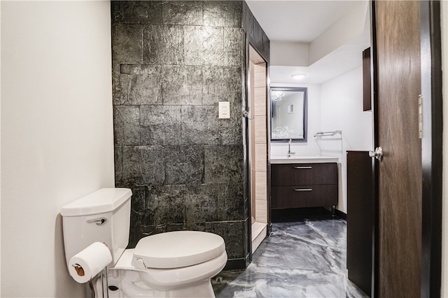 bathroom featuring a tile shower, tile walls, vanity, and toilet