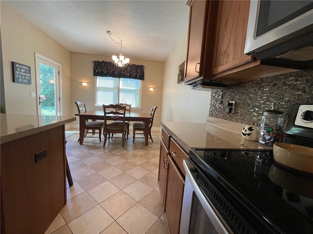 kitchen with stainless steel electric stove, backsplash, pendant lighting, a textured ceiling, and a chandelier