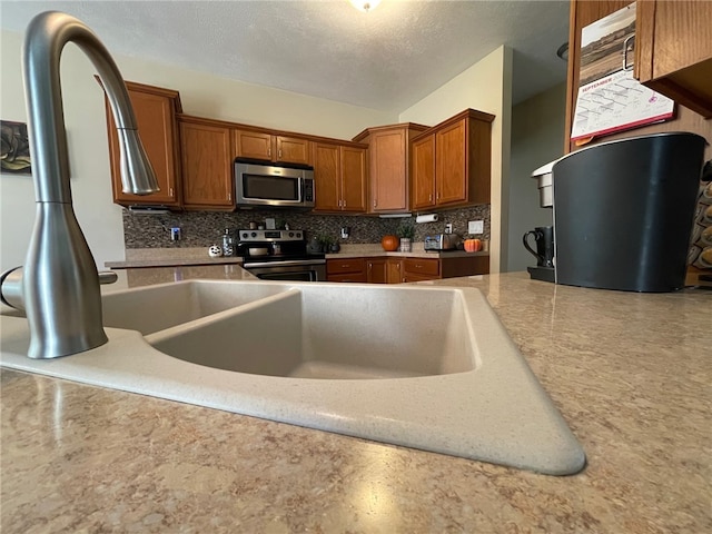 kitchen featuring appliances with stainless steel finishes, a textured ceiling, and tasteful backsplash