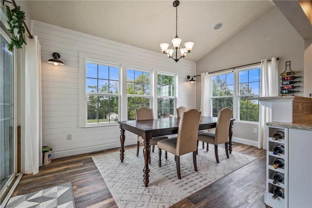 dining room with a notable chandelier, vaulted ceiling, wood walls, and dark hardwood / wood-style floors