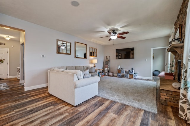 living room featuring ceiling fan, a fireplace, and dark hardwood / wood-style floors