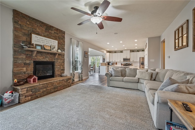 living room featuring light wood-type flooring, ceiling fan, and a fireplace