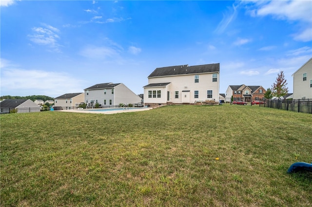 rear view of property featuring a yard and a fenced in pool