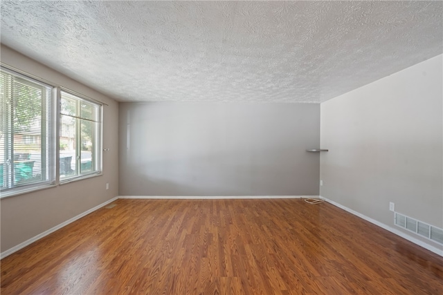 empty room featuring a textured ceiling and wood-type flooring