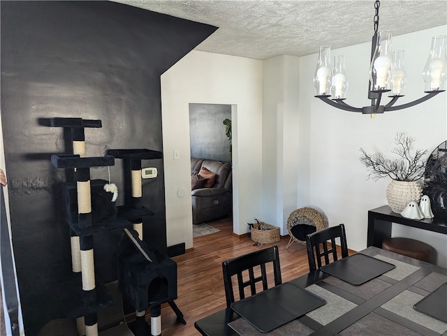 dining room with a textured ceiling, dark hardwood / wood-style floors, and a chandelier