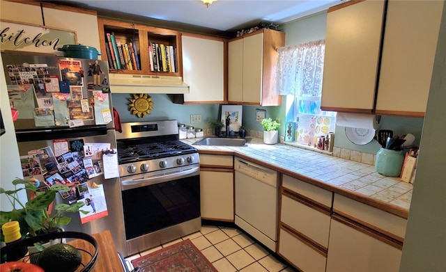 kitchen with light tile patterned floors, sink, appliances with stainless steel finishes, and tile countertops