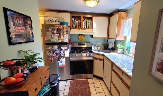 kitchen featuring light tile patterned floors, sink, appliances with stainless steel finishes, and tile counters