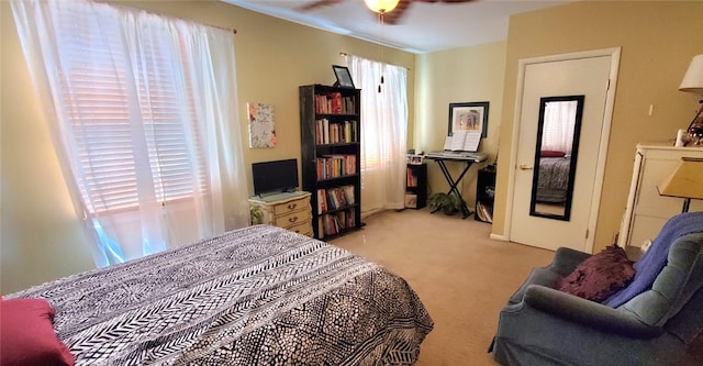 bedroom featuring ceiling fan, light colored carpet, and multiple windows