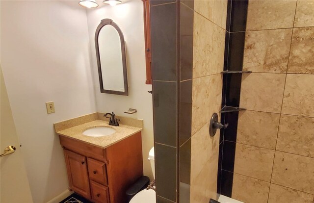 bathroom with a tile shower, vanity, and toilet