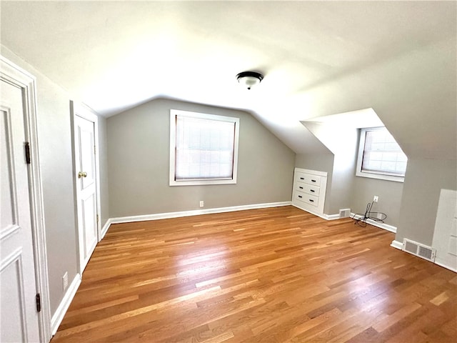 additional living space with light hardwood / wood-style flooring and vaulted ceiling