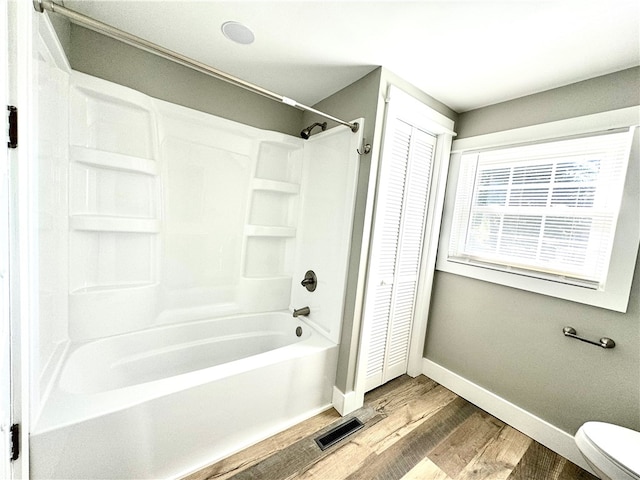 bathroom featuring toilet, hardwood / wood-style flooring, and shower / bathing tub combination