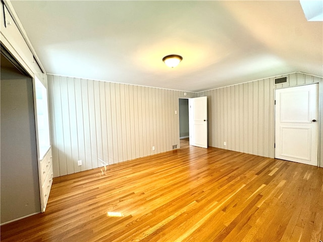 unfurnished bedroom with wood walls, hardwood / wood-style floors, and lofted ceiling