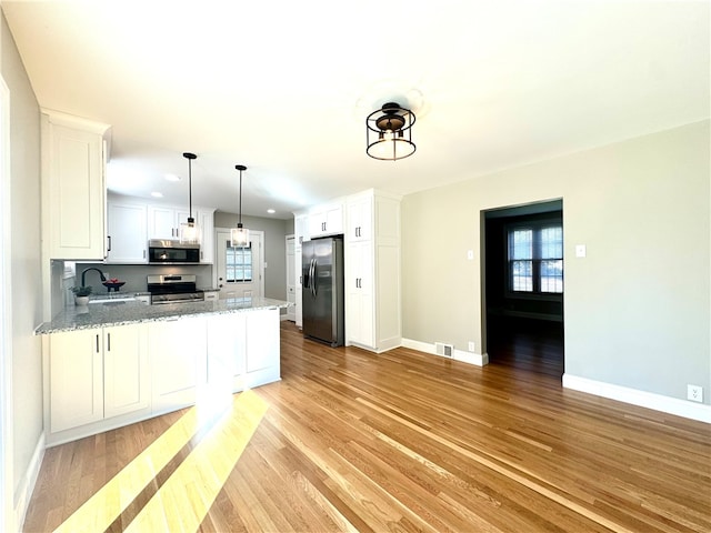 kitchen with light stone counters, white cabinetry, sink, light hardwood / wood-style floors, and stainless steel appliances