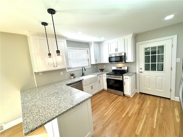 kitchen featuring kitchen peninsula, white cabinetry, sink, pendant lighting, and stainless steel appliances